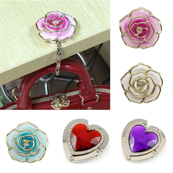 A set of heart-shaped metal foldable bag hooks in pink, gold, and purple colors.