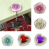 A collection of heart-shaped metal foldable bag hooks in various colors including pink, white, red, and purple.