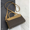A tan Michael Kors classic letter square crossbody bag with a brown and beige geometric pattern resting on a gray blazer.