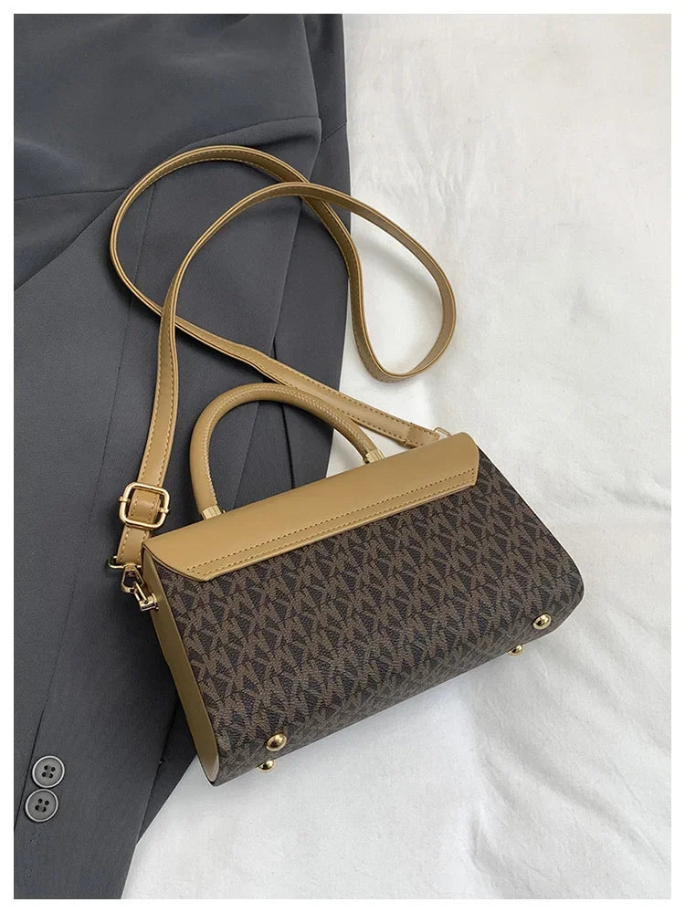 A tan Michael Kors classic letter square crossbody bag with a brown and beige geometric pattern resting on a gray blazer.