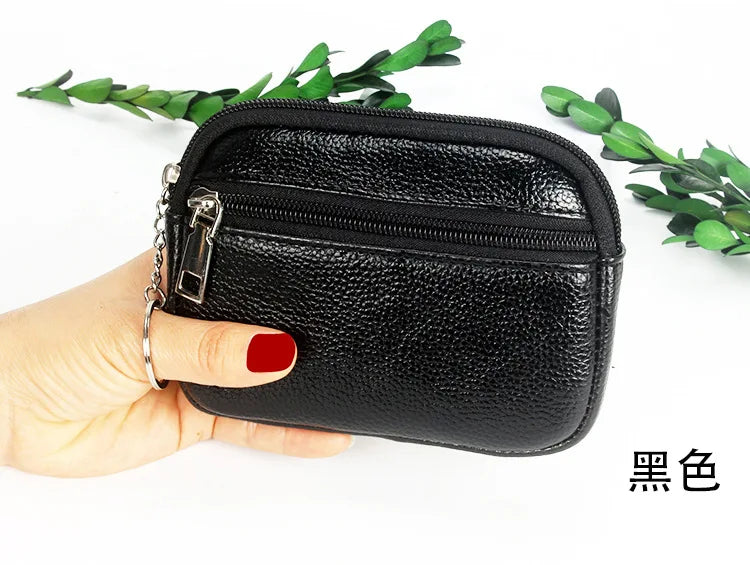 Black compact PU leather mini wallet with a silver keychain being held by a hand.