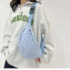 A light blue corduroy waist pack is worn by a woman in a gray hoodie.