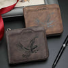 Cartera de cuero marrón con diseño de águila plateada, junto a un bolígrafo negro.