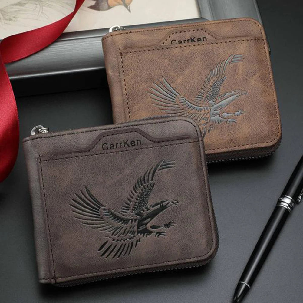 Cartera de cuero marrón con diseño de águila plateada, junto a un bolígrafo negro.