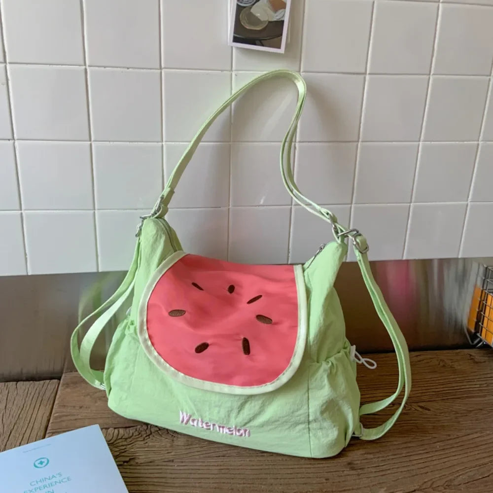 A lime green nylon messenger backpack shaped like a watermelon slice is displayed on a wooden surface.