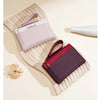 A pink leather wallet with a matching strap is displayed on a light wooden surface.