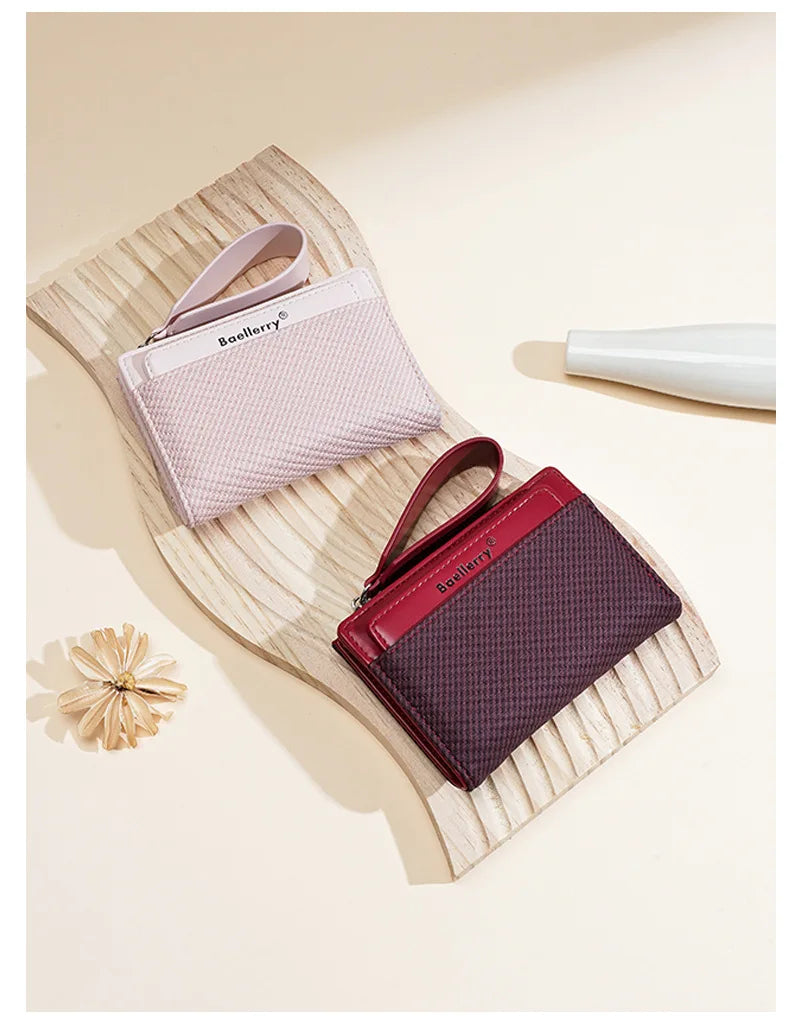 A pink leather wallet with a matching strap is displayed on a light wooden surface.