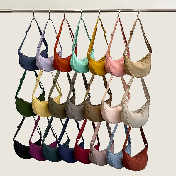 A display of various colored nylon zipper crossbody bags hanging on a rack.