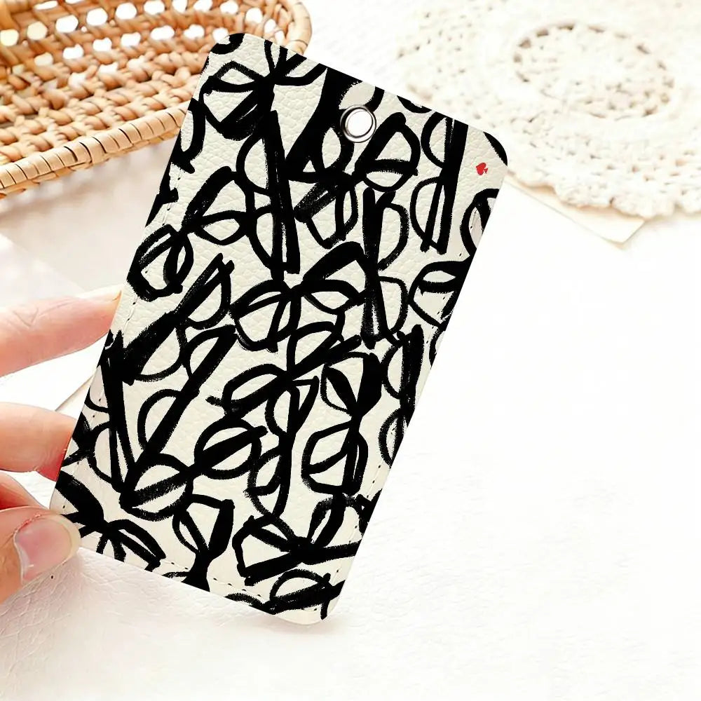 A black and white patterned card holder featuring a dense, abstract line drawing of flowers or leaves.