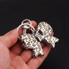 Silver leopard print bow and heart bag charm keychain held in a hand