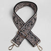Correa de cuero con patrón negro y beige y hebilla dorada, diseñada como correa ajustable para bolso cruzado ancho.