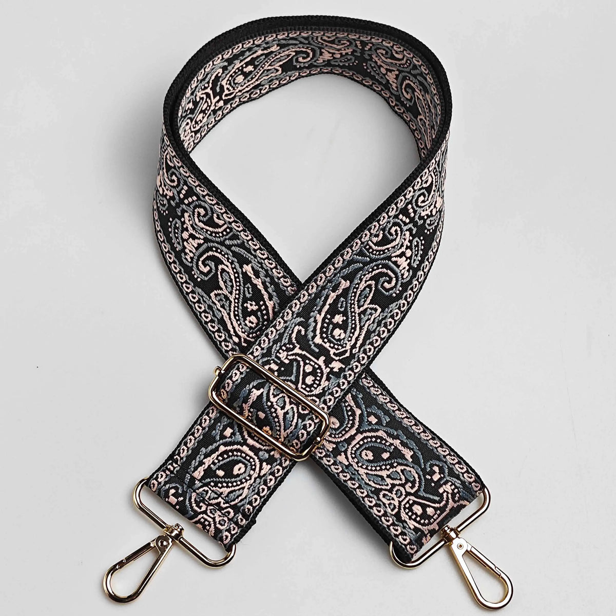 Correa de cuero con patrón negro y beige y hebilla dorada, diseñada como correa ajustable para bolso cruzado ancho.