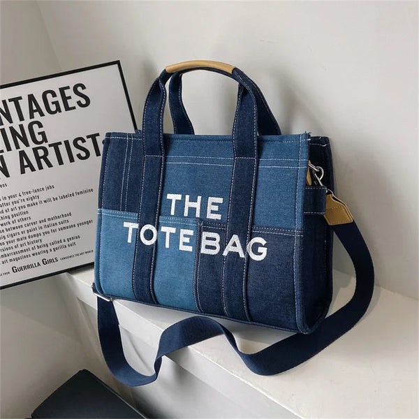 A dark blue canvas tote bag with white lettering is displayed on a white surface.