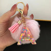 A custom initial letter keychain featuring a shiny resin pendant with a pink alphabet charm and tassels.