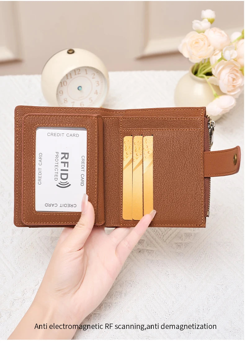 A brown leather wallet with a RFID-blocking card slot and coin pouch is held by a hand on a white surface.
