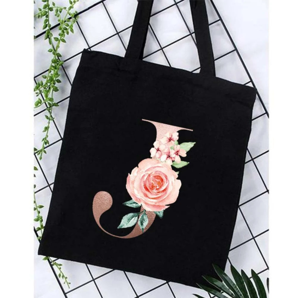 Black canvas tote bag featuring an alphabet floral print design.