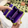 A hand holds a purple and lime green coin purse wallet open, displaying the interior.