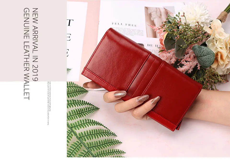 A red genuine leather wallet is shown open, resting on a light pink background next to floral arrangements and green foliage.