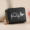 Black leather zipper wallet with a white heart and butterfly line art print resting on a light surface.