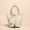 Helles beige Leder-Bucket-Bag mit Schnurverschluss und goldfarbenem Zierwerk.