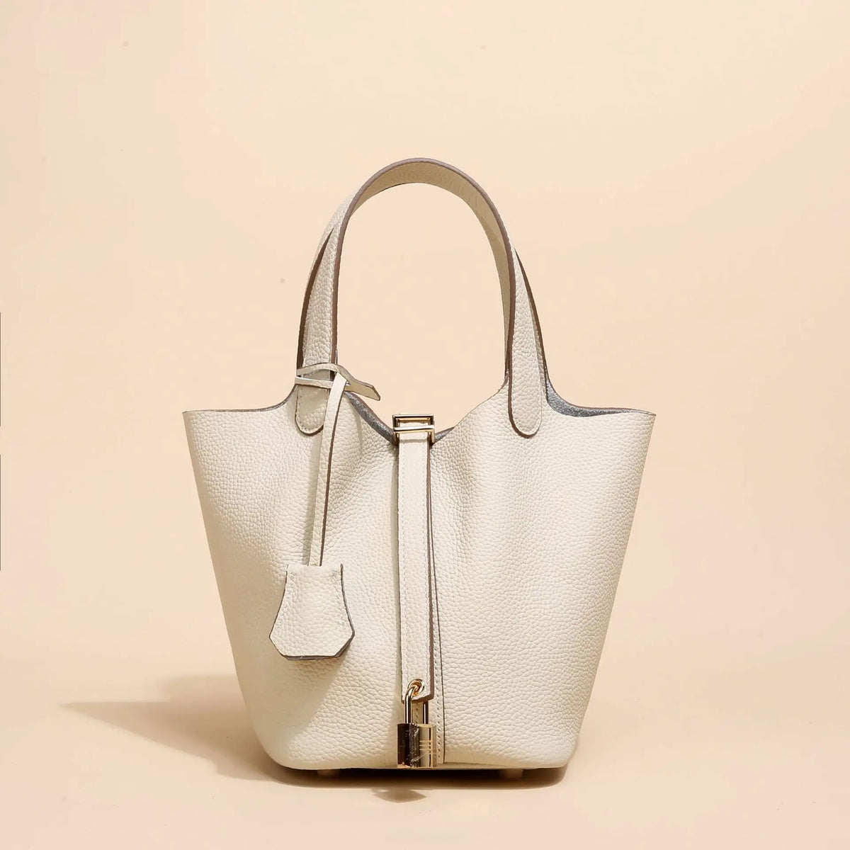 Helles beige Leder-Bucket-Bag mit Schnurverschluss und goldfarbenem Zierwerk.