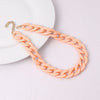 A delicate, rose gold-toned acrylic chain necklace with a lobster clasp displayed on a white plate.