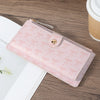 A pink folding multi-card wallet with a floral pattern is shown on a wooden surface.