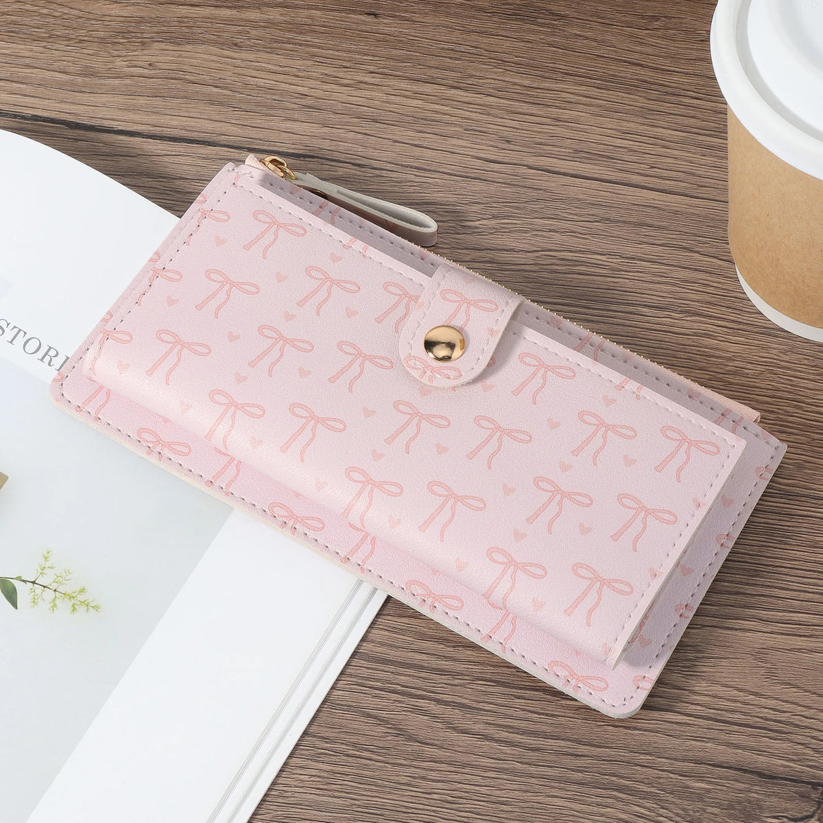A pink folding multi-card wallet with a floral pattern is shown on a wooden surface.