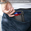 A hand places a black carbon fiber slim wallet into the pocket of dark blue jeans.