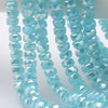 A close-up of light blue aquamarine faceted crystal glass beads shaped like wheels arranged in strands.