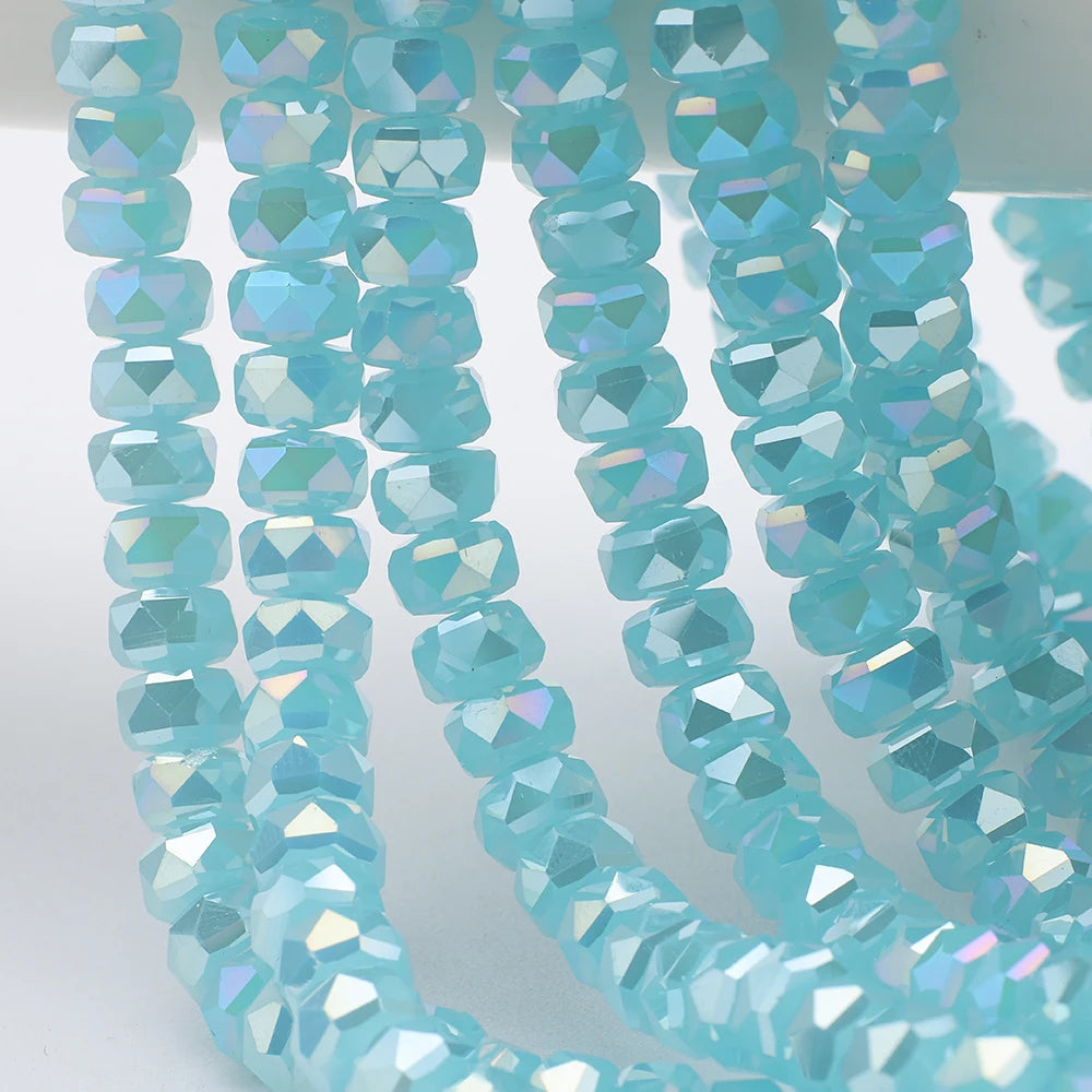 A close-up of light blue aquamarine faceted crystal glass beads shaped like wheels arranged in strands.