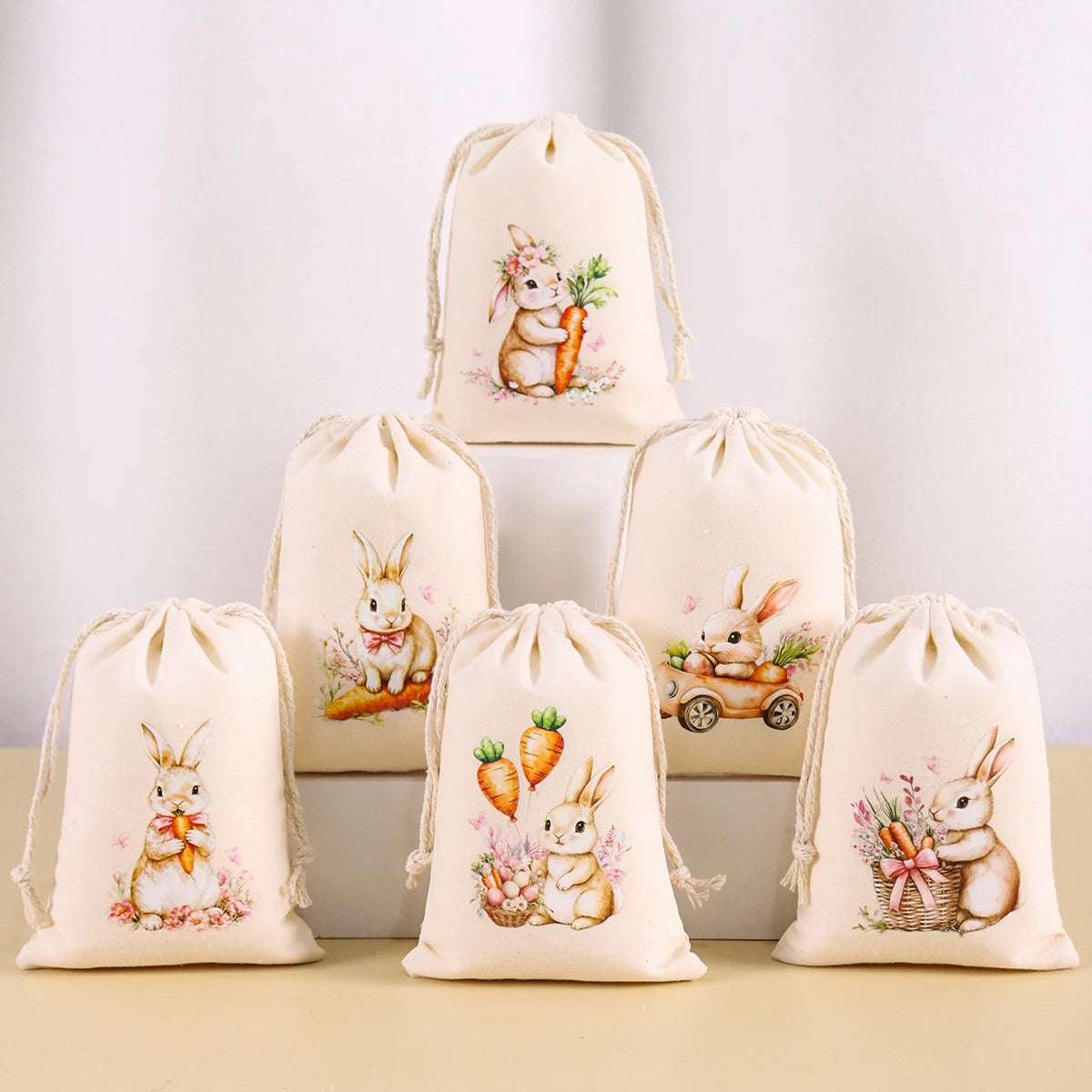 A set of six beige drawstring gift bags featuring illustrations of Easter bunnies and carrots.