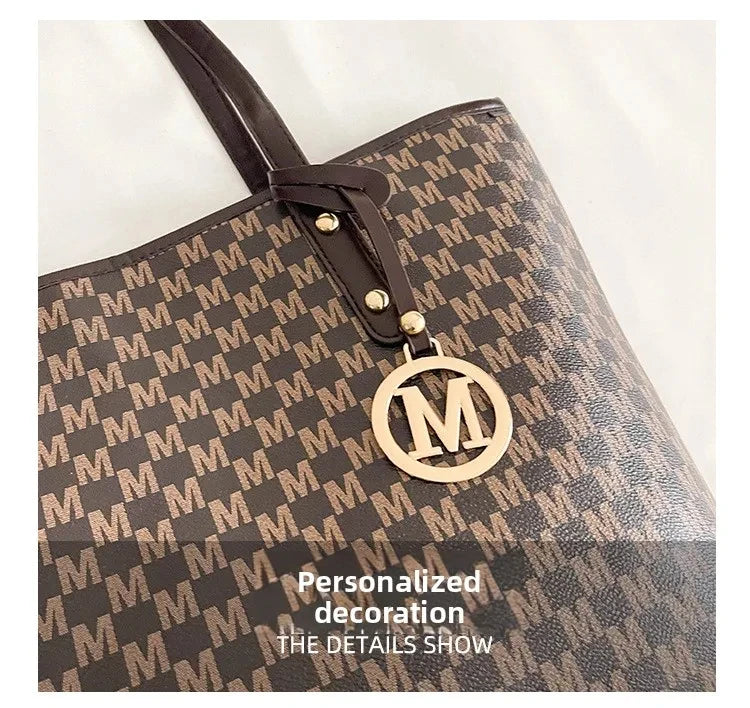 A close-up of a brown faux leather tote bag with a monogram print and gold hardware.