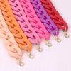 A display of multiple strands of colorful acrylic statement choker necklaces in shades of orange, pink, and purple.