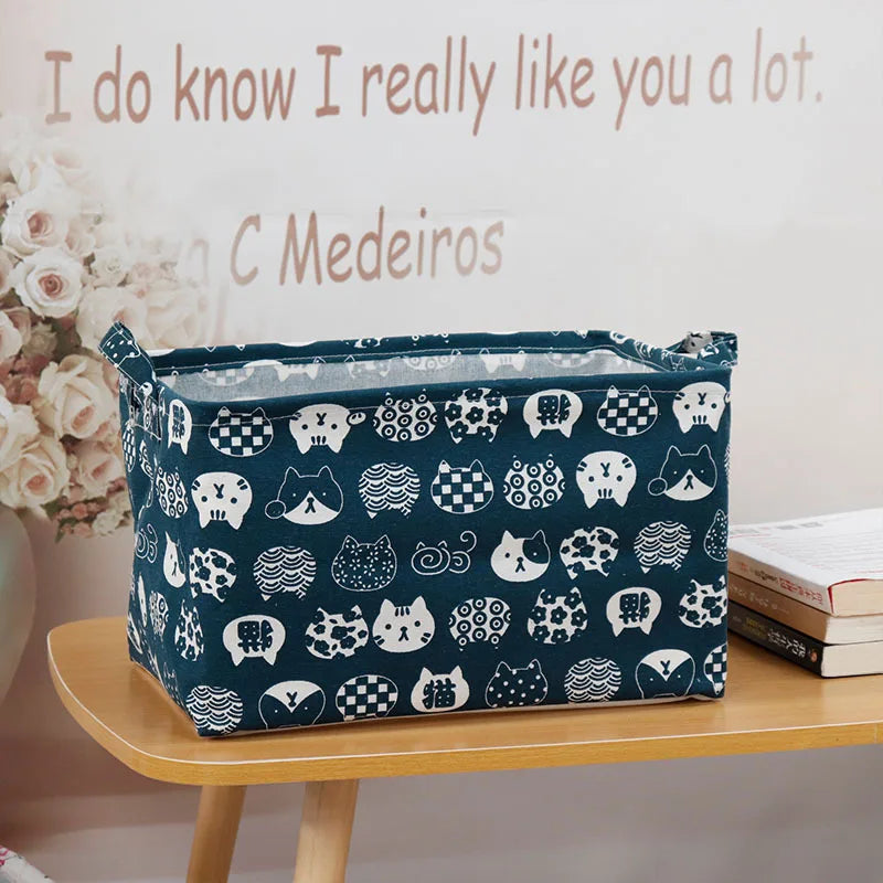 A dark blue fabric storage basket with various animal-themed patterns sits on a wooden shelf.