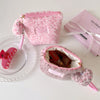 A pink leopard print makeup bag with a zipper and pink strap resting on a white surface.