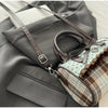 A brown leather crossbody bag with a piano print is shown resting on a gray blazer.