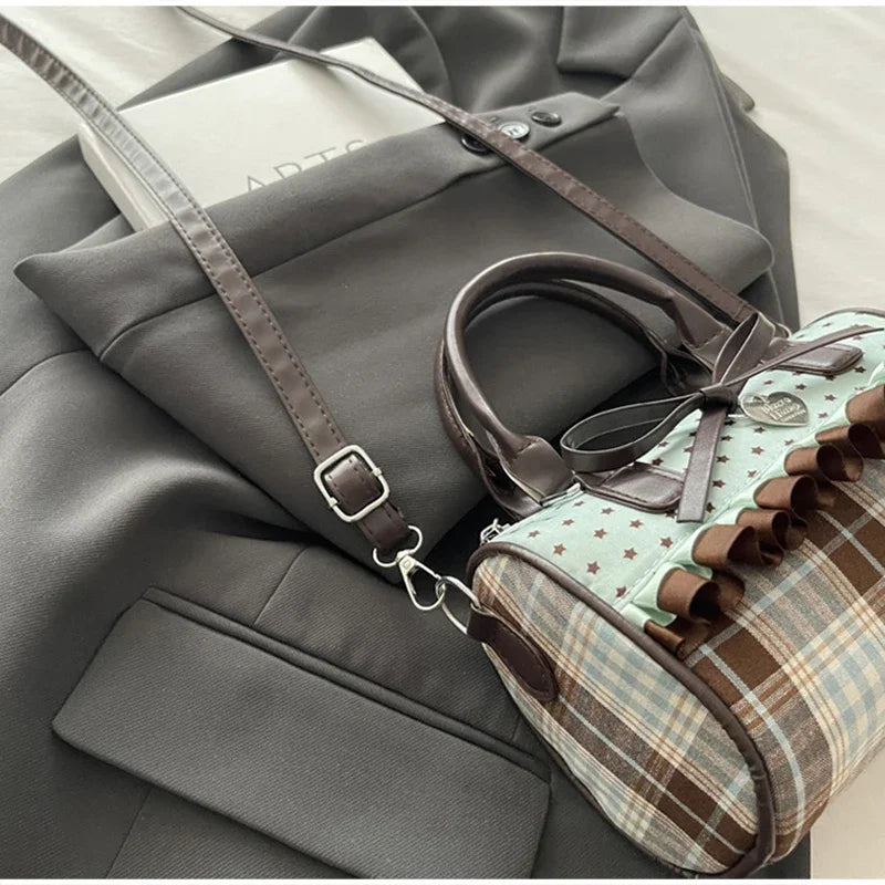 A brown leather crossbody bag with a piano print is shown resting on a gray blazer.