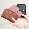 A hand holds a brown leather wallet and a pink leather wallet, demonstrating RFID protection.
