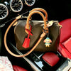A brown genuine cowhide leather shoulder strap is shown attached to a dark brown leather handbag in a car interior setting.