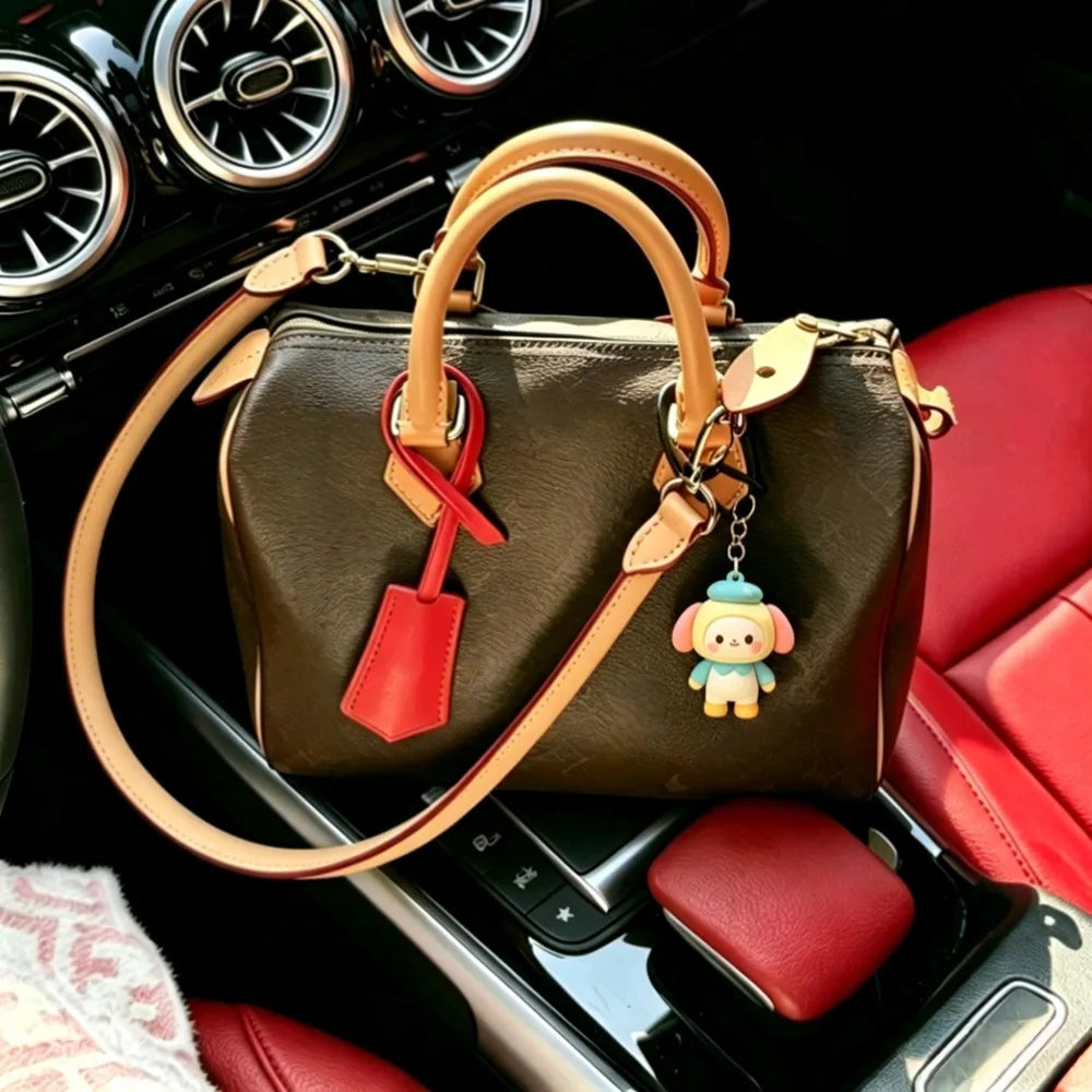 A brown genuine cowhide leather shoulder strap is shown attached to a dark brown leather handbag in a car interior setting.