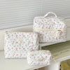 A set of quilted white cotton makeup organizers, including a zippered pouch and a larger storage box.