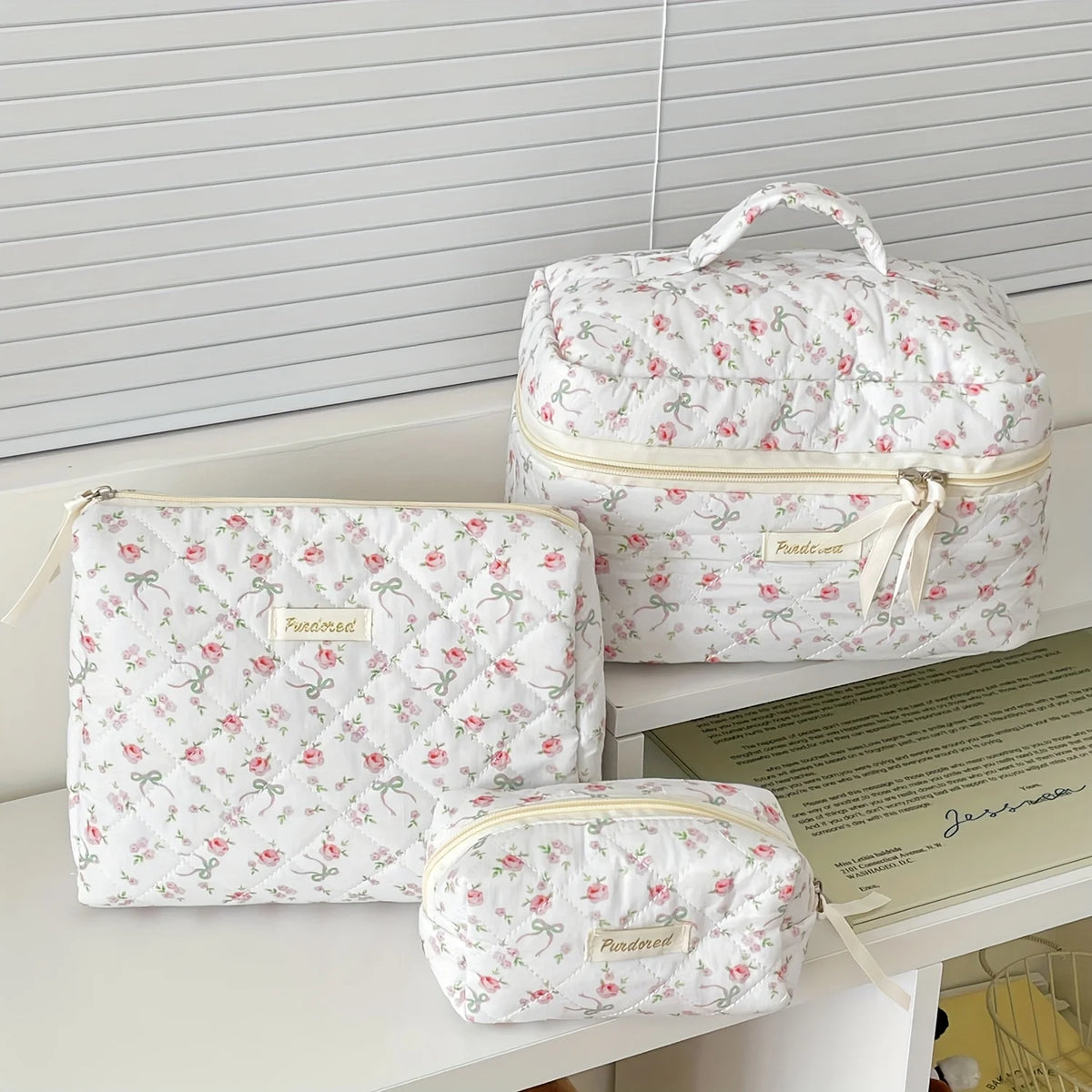 A set of quilted white cotton makeup organizers, including a zippered pouch and a larger storage box.