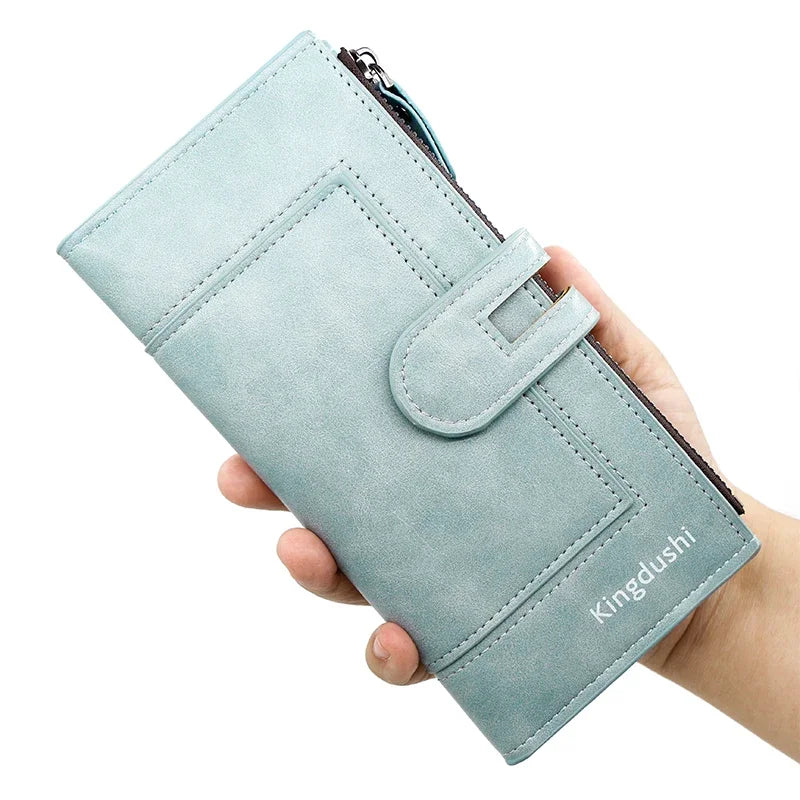 A hand holds a light blue suede phone and card wallet with a flap closure.
