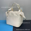 A cream-colored insulated cooler lunch bag with a detachable strap is shown against a dark background.