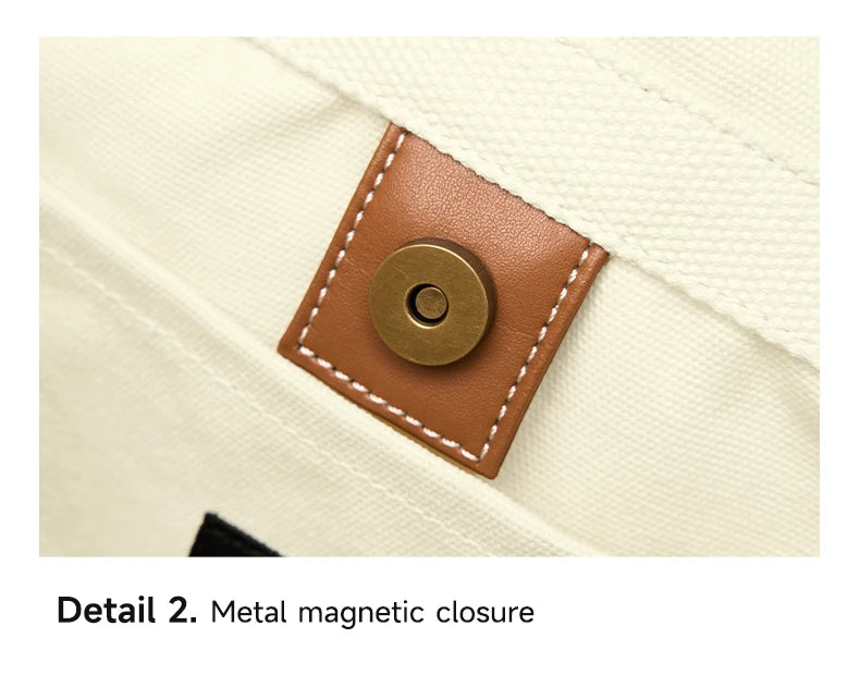 Detail of a brown metal magnetic closure on a cream-colored fabric.