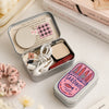 A portable metal storage box with a sardine print design and white accessories is shown on a light surface.