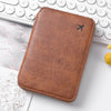 A brown leather passport and document holder with a small airplane embossed on the cover, resting on a white keyboard.