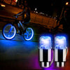 A pair of bright blue and purple LED tire valve stem lights are shown illuminating a dark surface.