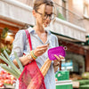 A young woman holds a purple Iris checkered wallet with an ID window while shopping.